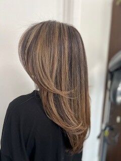 This look is all about soft contrast and seamless dimension. Liz blended warm brunette tones with sun-kissed blonde ribbons to create movement that catches the light from every angle. The layers add volume without sacrificing sleekness—perfect for clients